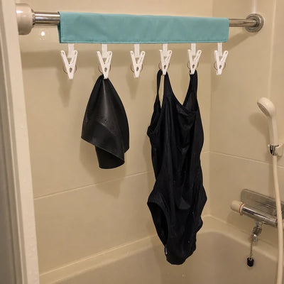 ホテルのユニットバスのレールに、水着と水泳帽を干している写真。